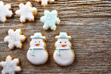 Iced, Santa and snowflake decorated Christmas cookies on rustic wood surface with dramatic lighting