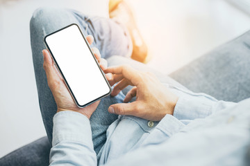 Mockup image blank white screen cell phone.man hand holding texting using mobile on safa at home office.background empty space for advertise text.people contact marketing business,technology 