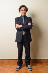 Obraz na płótnie Canvas Full body shot of happy Japanese businessman smiling with arms crossed