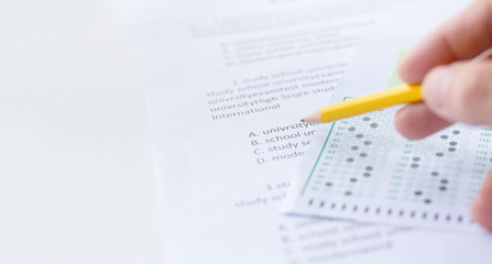 Obraz premium high school,university student study.hands holding pencil writing paper answer sheet.sitting lecture chair taking final exam attending in examination classroom.concept scholarship for education abroad