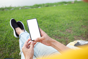 Mockup image blank white screen cell phone.woman hand holding texting using mobile at outdoor park.background empty space for advertise text.people contact marketing business,technology 