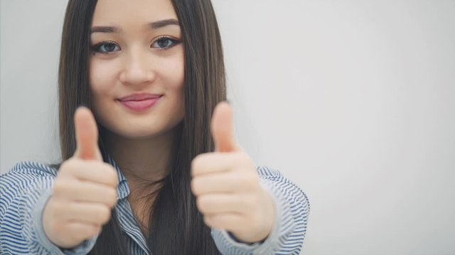 Cropped face of young asian girl looking up at the camera, giving thumbs up, smiling lovely.
