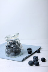 glass can of blueberry on white wooden background