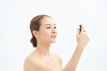 Beautiful asian woman applying spray water on face isolated white background.