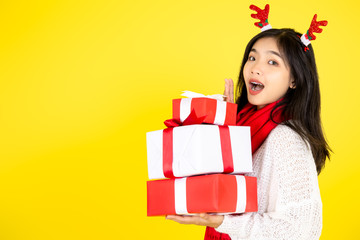 Happy Asian teenager girl holding gift boxes on yellow  background.