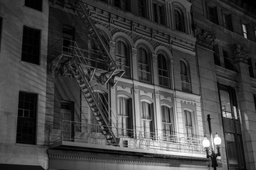 vintage black and white of an old building and street light at night with fire escape. 