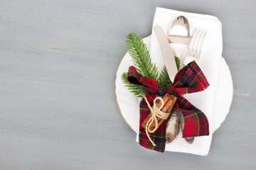 Festive table setting for Christmas dinner on a gray wooden background with place for text. The concept of winter holidays. Flat layout.