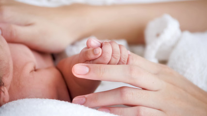 Obraz na płótnie Canvas Cute newborn baby touching mother's hand.