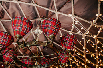 a large chandelier in a classic Scottish style red and black cage, decoration of a brown canvas with a lamp and braided ropes