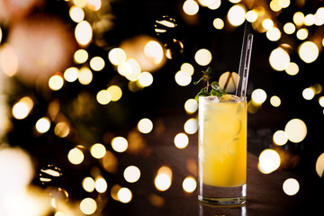 Screw driver cocktail with fresh mint on the dark background. Shallow DOF with festive bokeh lights
