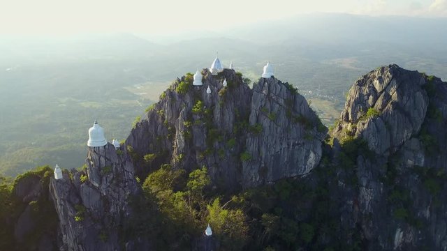 Spectacular aerial view of floating pagodas on the mountain cliff at Wat Chaloem Phra Kiat in Chae Hom District, Lampang province, Thailand. 4K drone video