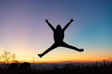Silhouette of happy human jumping playing on mountain at sunset