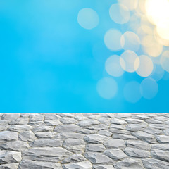 Gray stone top and blurry blue water bokeh background