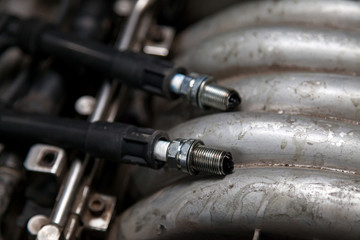 Spark plugs with high voltage wires on the engine under the hood of a car during diagnosis and repair in a workshop for vehicles. Auto service industrial.