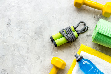 Gym equipment - dumbbells, jump rope - frame on grey background top-down copy space