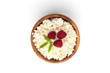 Cottage cheese with raspberry in wooden bowl isolated on white background.