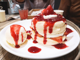 Homemade fluffy pancake and sweet syrup - Delicious pancakes with strawberry sauce and ice cream on dining table in the cafe restaurant