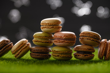 French macaroons on green grass and on a starry sky and moon. Delicious sweets
