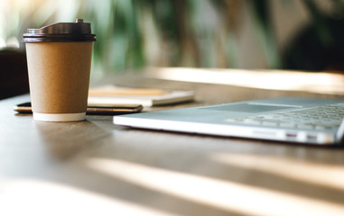 Place of work on wooden desk with laptop, cup of coffee, notebook and mobile phone