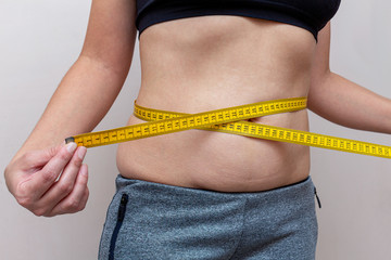woman measures the waist with a yellow tape. Diet fitness concept.