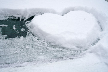Fototapeta na wymiar close up on drawing hearts on car windshield after snow