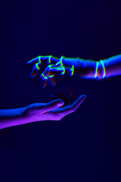 Woman and robot's hands as a symbol of connections between people and technology. Neon colors.