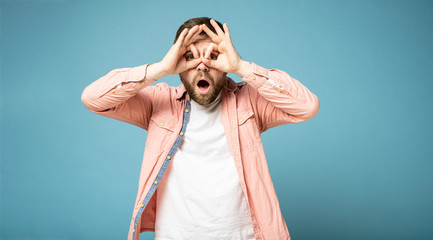 Strange bearded man makes a gesture like binoculars, pressing his hands to face, eyes look through...