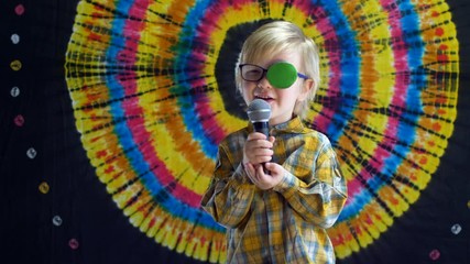 Portrait of funny child in new glasses with green spot to correct strabismus and microphone Orthopedic Boys Eye Patches eyewear for strabismus (lazy eye)