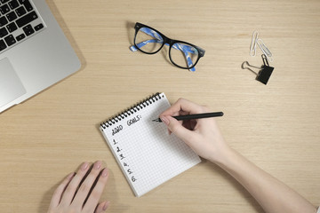 2020 goals. Workspace with laptop, girls hands, notepad. View from above. Copy space. Flat lay