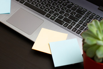 Communications flat lay with blank sheet of paper stickers  and laptop on a black desk with and...