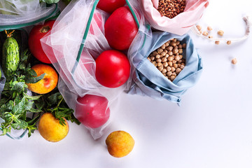 Seasonal fruits and vegetables on white. Raw organic fresh food from market. Zero waste shopping. Reusable grocery bags