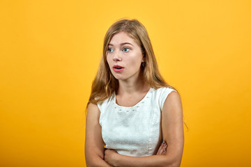 Fototapeta premium Scared caucasian young woman keeping hands crossed, looking confused with opened mouth over isolated orange background wearing white shirt. Lifestyle concept