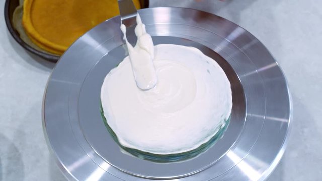 Icing a cake with whipped cream and a spatula