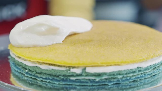 Scooping whipped cream on to colored cake layers