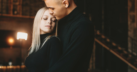 Portrait of a lovely young couple embracing while man is embracing her girlfriend from back indoor.