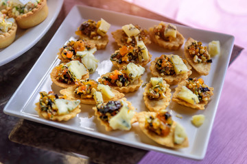 Tartlets with dried fruits and cheese, close-up. Sweet table at festive dinner. Prunes, raisins, dried apricots, nuts - filling for cakes.