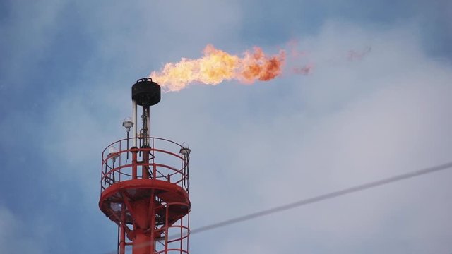 fume of fire on flare stack to burning heat gas, pollution in environment concept, for power and safety in petrochemical, chemical refinery or power plant in industrial zone, blue sky