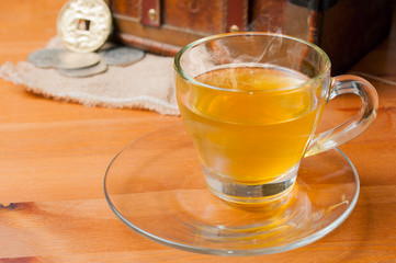 Green tea on a glass cup on wooden table sorrounded by antique objects