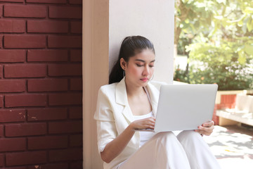 Confident young Asian business woman using laptop for job at outside office.