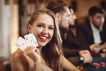 Girl with cards in her hands smiles at winning poker in a casino.