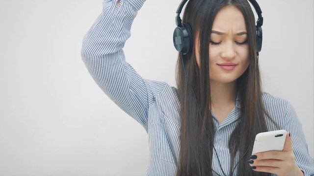 Inspired young asian girl in headphones, listening to the music, dancing, smiling to the camera.