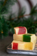 A fine nougat with sliced Pieces of glace fruit, delicious and famous Christmas sweet on wooden board with Christmas decoration.