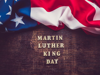 Wooden unpainted letters of the alphabet on a dark background. Martin Luther King Jr. Day. Top view, close-up. National holiday concept