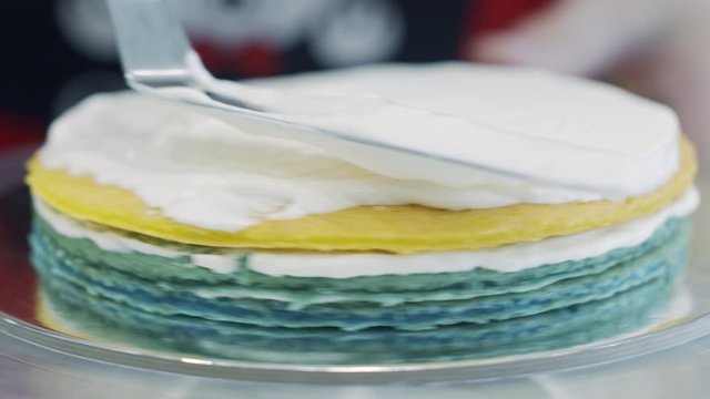 Scooping whipped cream on to colored cake layers