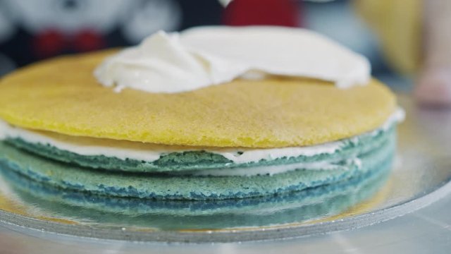 Scooping whipped cream on to colored cake layers