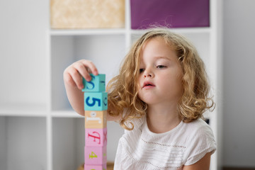 Portrait of young girl playing with toy blocks at home
