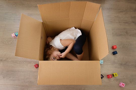 Cute little girl hiding in cardboard box