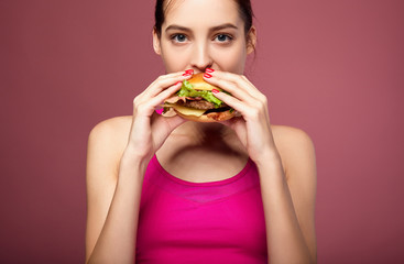 Good-looking woman eating cheeseburger.