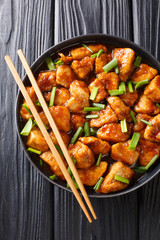 Mongolian chicken in a spicy sweet sauce with green onions close-up in a plate. Vertical top view