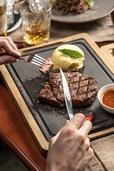 man eating steak with mashed potato and tomato sauce at restaurant